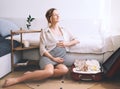 Pregnant woman is packing suitcase for maternity hospital getting ready for childbirth. Happy young mother with travel luggage of Royalty Free Stock Photo