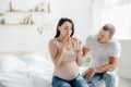 Pregnant woman with pain taking pill with water in bedroom with husband near Royalty Free Stock Photo