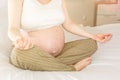 Pregnant woman peacefully meditating on a bed