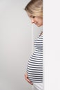 Pregnant woman peeking out of white wall Royalty Free Stock Photo