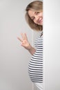 Pregnant woman peeking out of white wall Royalty Free Stock Photo