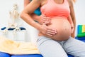 Pregnant woman with physical therapist sitting on couch Royalty Free Stock Photo