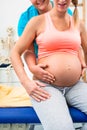 Pregnant woman with physical therapist sitting on couch Royalty Free Stock Photo