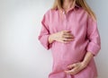 a pregnant woman in a pink shirt stands on a white background Royalty Free Stock Photo