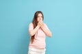 pregnant woman in pink t-shirt on blue background, toxicosis during pregnancy