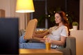 Pregnant woman with pizza box watching tv at home Royalty Free Stock Photo