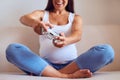 Pregnant woman playing computer game with joystick