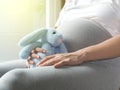 Pregnant woman is playing the rabbit doll in her hand.