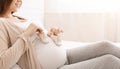 Pregnant woman playing with tiny shoes, stepping on belly Royalty Free Stock Photo