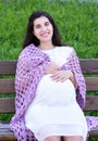 Pregnant woman portrait on outdoor, happy maternity concept, sit on bench in city park, summer season, green grass background Royalty Free Stock Photo