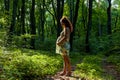 A pregnant woman is posing in the forest