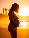 Pregnant woman on ocean beach at sunrise or sunset Royalty Free Stock Photo