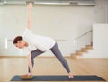 Pregnant woman is engaged in yoga. Revolved side angle pose or Parivrtta Parsvakonasana