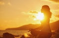 Pregnant woman practicing yoga in lotus position on beach at sun Royalty Free Stock Photo