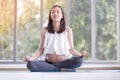 Young pregnant woman practicing yoga while sitting in lotus position at home Royalty Free Stock Photo