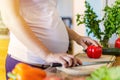 Pregnant woman preparing healthy food in kitchen lit by sunlight Royalty Free Stock Photo