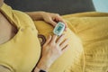 Pregnant woman with pulse oximeter on finger. Doctor measuring oxygen saturation level while visiting expectant mother Royalty Free Stock Photo