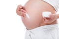 Pregnant woman putting cream on her belly