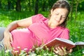 Pregnant woman reading book on grass Royalty Free Stock Photo