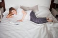 A pregnant woman is reading a book about raising a child, reclining on a wide bed with pillows. Royalty Free Stock Photo