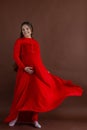 Pregnant woman in red flying dress holding her belly Royalty Free Stock Photo