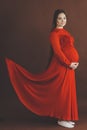 Pregnant woman in red flying dress holding her belly Royalty Free Stock Photo