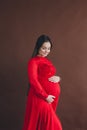 Pregnant woman in red flying dress holding her belly Royalty Free Stock Photo