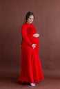 Pregnant woman in red flying dress holding her belly Royalty Free Stock Photo