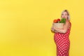 pregnant woman in a red polka dot dress holds a basket of vegetables in her hands on a yellow background with copy space Royalty Free Stock Photo