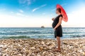 Pregnant woman with red umbrella on the beach