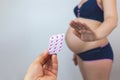 A pregnant woman refuses to take pills. White background