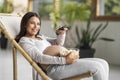 Pregnant Woman Relaxing In Chair At Home, Watching Tv And Eating Popcorn Royalty Free Stock Photo