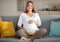 Pregnant Woman Relaxing On Couch At Home, Watching Tv And Eating Popcorn Royalty Free Stock Photo