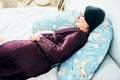 Pregnant woman relaxing or sleeping with belly support pillow in bed. Royalty Free Stock Photo