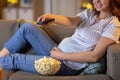 pregnant woman with remote control watching tv Royalty Free Stock Photo