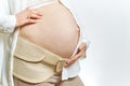 Pregnant woman`s belly faceless and hands close-up isolated. Maternity Belt Pregnancy Abdomen Support Abdominal Binde Royalty Free Stock Photo