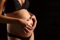 Pregnant woman`s belly and hands with a heart on her stomach Royalty Free Stock Photo
