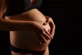 Pregnant woman`s belly and hands with a heart on her stomach Royalty Free Stock Photo