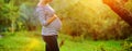 Pregnant woman on second trimester posing in sunny garden in the backlit