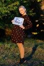 Pregnant woman on second trimester posing in sunny garden, shows a slogan its a boy