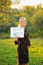 Pregnant woman on second trimester posing in sunny garden, shows a slogan its a boy