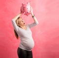 Pregnant woman in shock shaking piggy bank Royalty Free Stock Photo