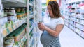 Pregnant woman shopping baby formula. Young pregnant woman buying infant baby formula milk on supermarket background Royalty Free Stock Photo