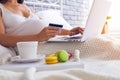 Pregnant woman shopping online in bedroom Royalty Free Stock Photo