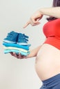 Pregnant woman showing clothing for newborn, expecting for baby concept Royalty Free Stock Photo
