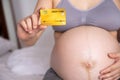 Pregnant woman showing credit card on bed in bedroom Royalty Free Stock Photo