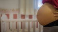Pregnant woman showing her belly from the side in a baby room Royalty Free Stock Photo