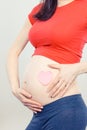 Pregnant woman showing pink heart on her belly. Expecting for newborn. Extending family Royalty Free Stock Photo