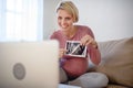 Pregnant woman showing ultrasound photo of her baby to webcam. Royalty Free Stock Photo