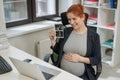 A pregnant woman shows a photo from an ultrasound scan of the fetus via video link in the office. Royalty Free Stock Photo